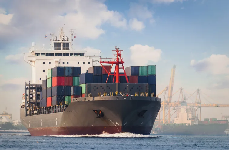 Container vessel under way with a full deck load of shipping containers