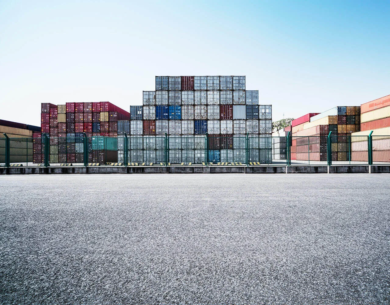 Secured open yard stacked several containers high behind perimeter fencing