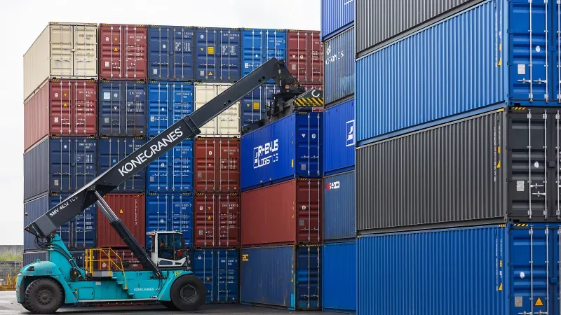 Reach stacker lifting a shipping container in a stacked container yard